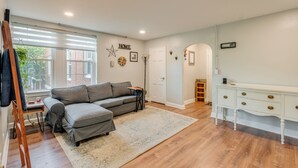 Un salon avec un canapé d’angle gris, une console blanche et un plancher en bois.