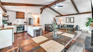 A spacious kitchen with wooden beams, a dining area with a large wooden table, and a living room with a sofa and a coffee table. - Private Hot Tub: Tree-lined Poconos Home! (Pocono Summit)