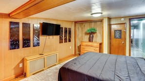 Habitación de hotel con paneles de madera, una cama, un televisor, obras de arte en la pared y un cartel en la puerta.
