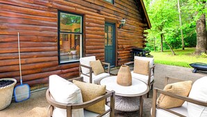 A log cabin with a patio area featuring outdoor furniture and a table.