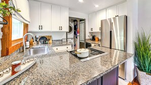 A modern kitchen with granite countertops, stainless steel appliances, and white cabinetry.