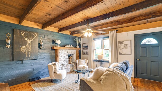 A cozy living room with a fireplace, comfortable seating, and a ceiling fan.