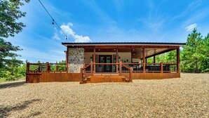 Une cabane rustique avec une façade en pierre, une terrasse en bois et un porche abrité.