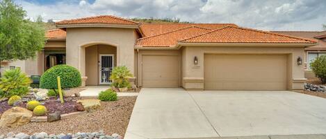 A residential house with a tiled roof, a garage, and a landscaped front yard with rocks and cacti.
