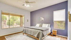 A bedroom with a bed, a window, a ceiling fan, and a nightstand. - Spacious Home in Saddlebrooke 55-plus Community! (Saddlebrooke)