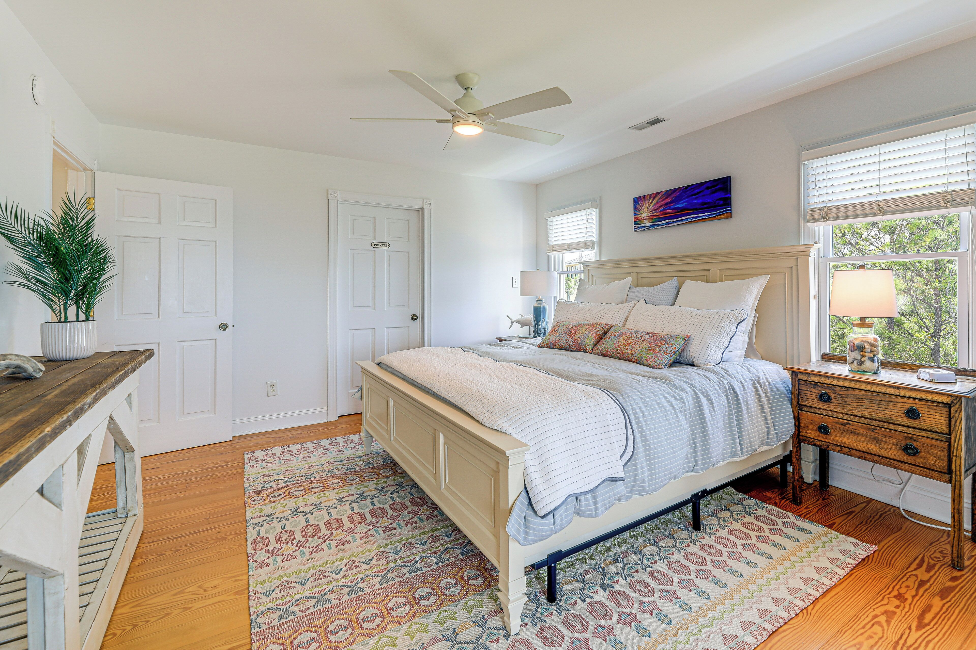A bedroom with a bed, bedside table, lamp, and a ceiling fan.