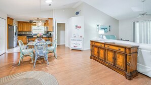 Une cuisine spacieuse avec des meubles de rangement en bois, un coin repas avec des chaises et un grand meuble en bois.