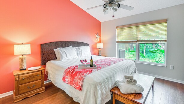 Une chambre à coucher avec un lit, une table de chevet, une lampe et une fenêtre avec des stores.