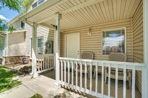 A house with a covered porch, a white door, and a small seating area with two chairs.