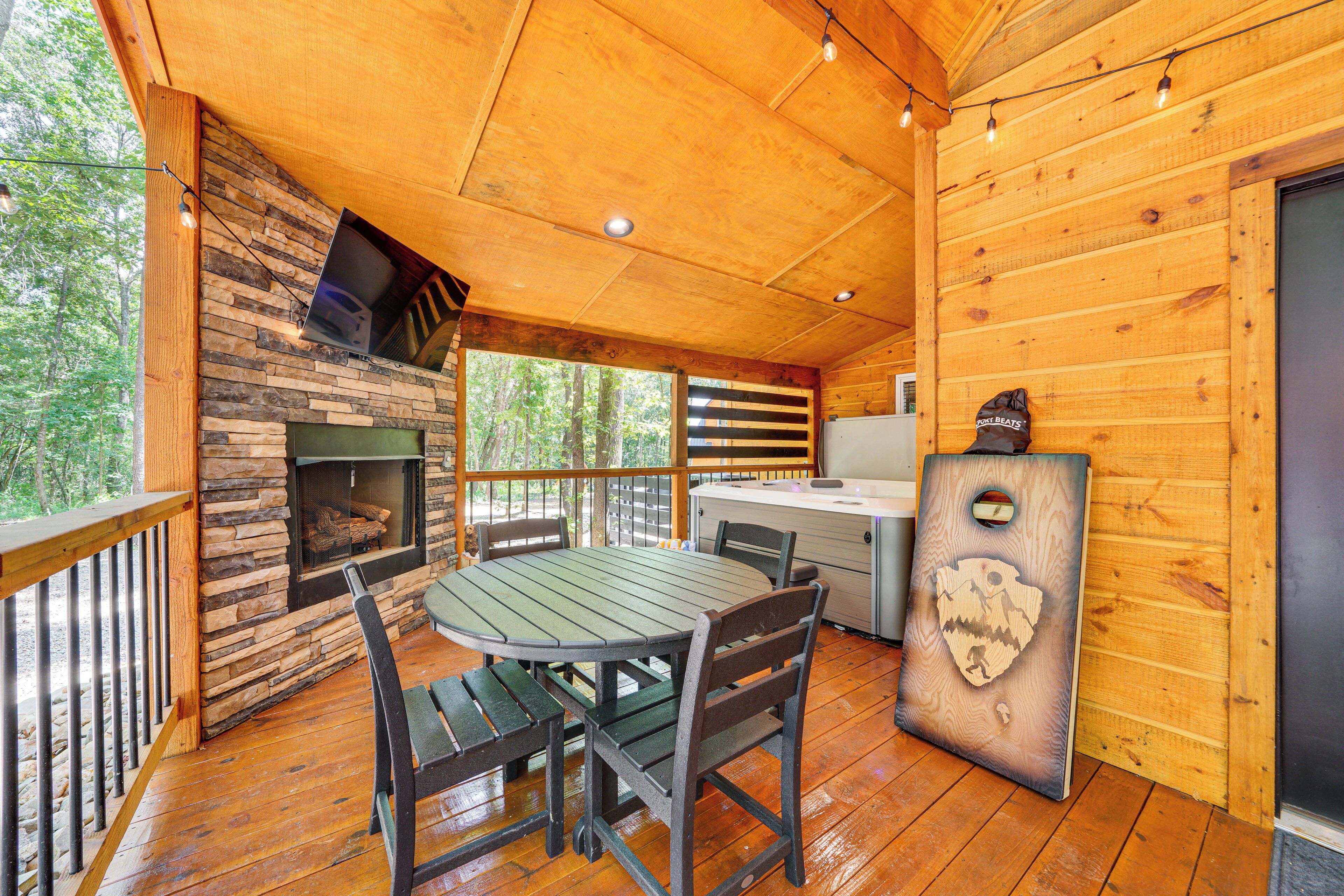 Una cabaña de madera con chimenea de piedra, una mesa de comedor con sillas y una pequeña cocina.