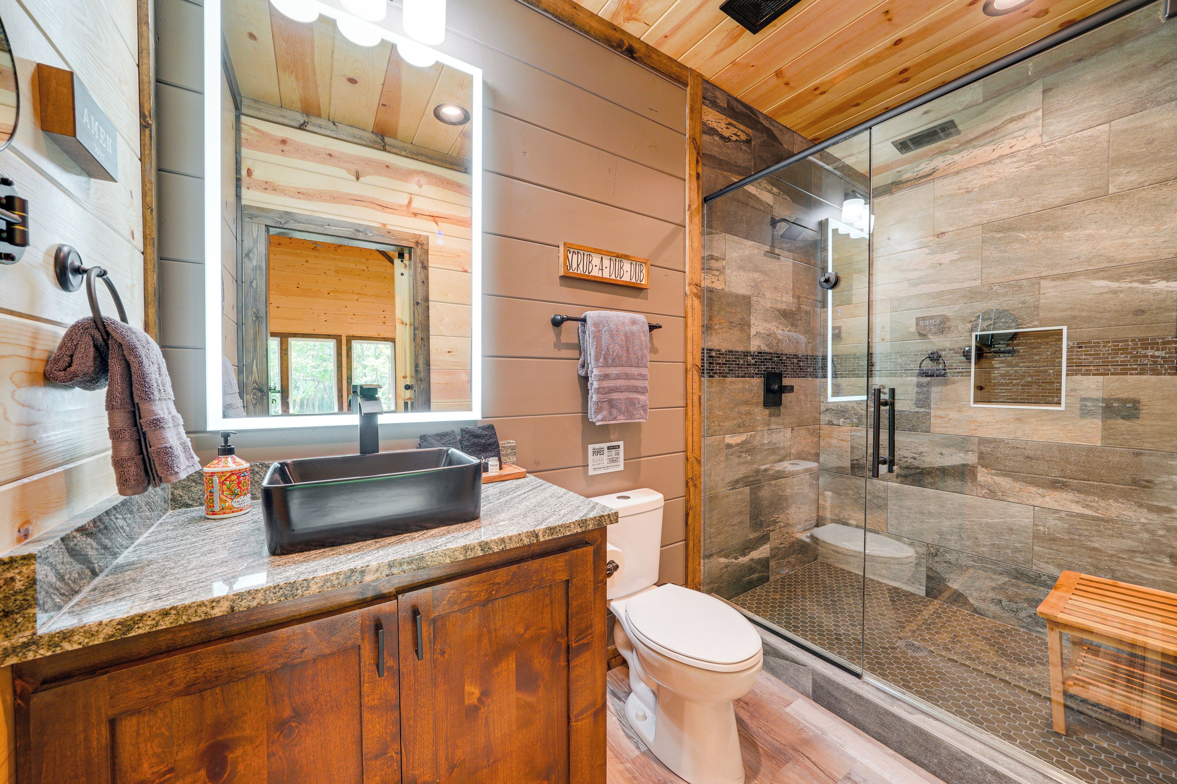 A modern bathroom with a wooden vanity, a glass shower enclosure, and a visible toilet.