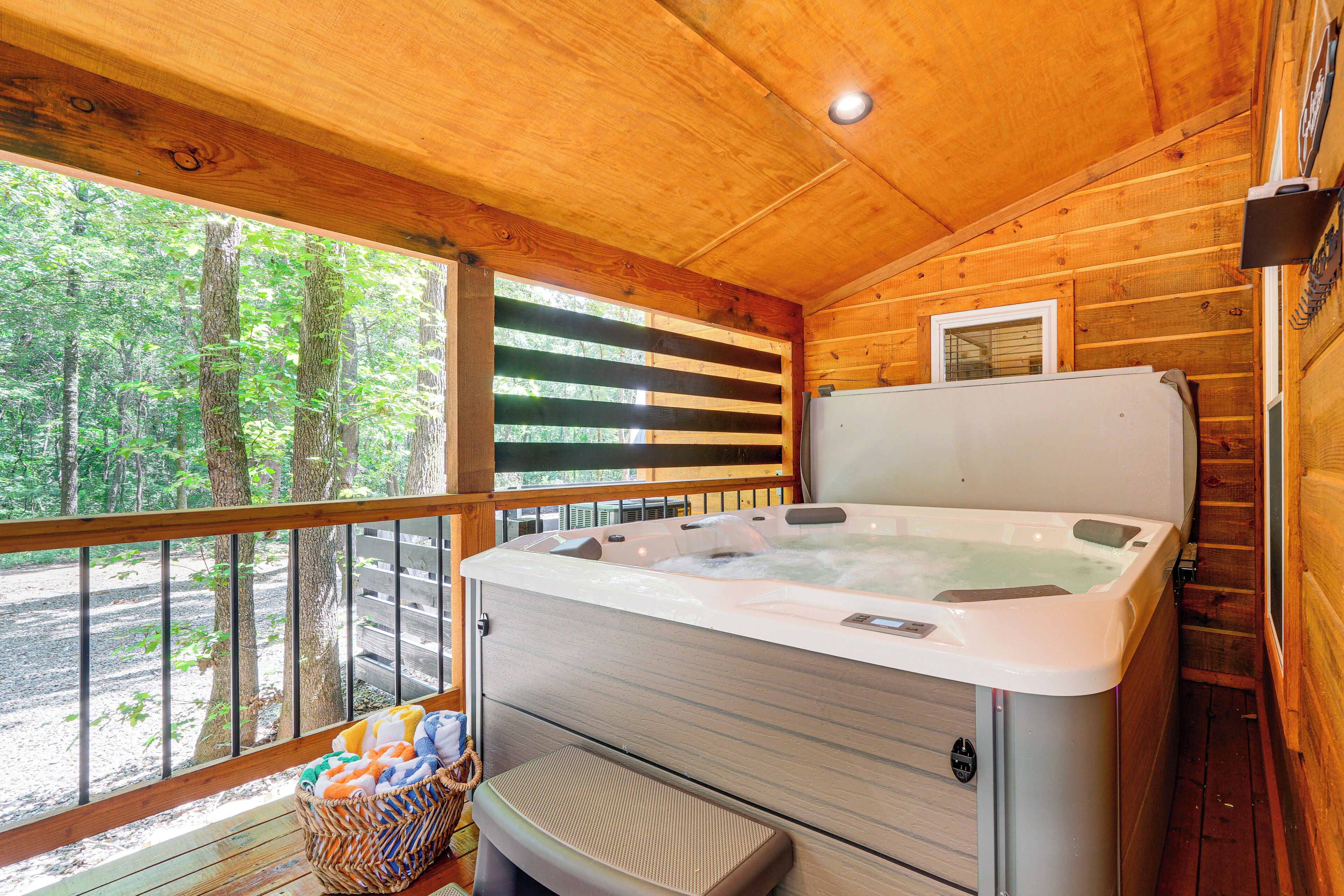 A wooden cabin with a hot tub, a bench, and a basket of towels.