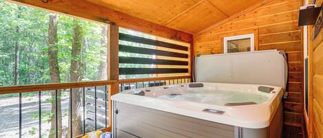 A wooden cabin with a hot tub, a bench, and a basket of towels.