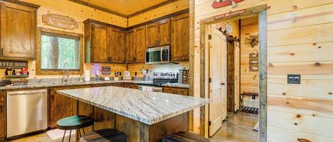 A kitchen with wooden cabinets, a granite countertop, a coffee bar, and a sign that says "This kitchen is seasoned with love."