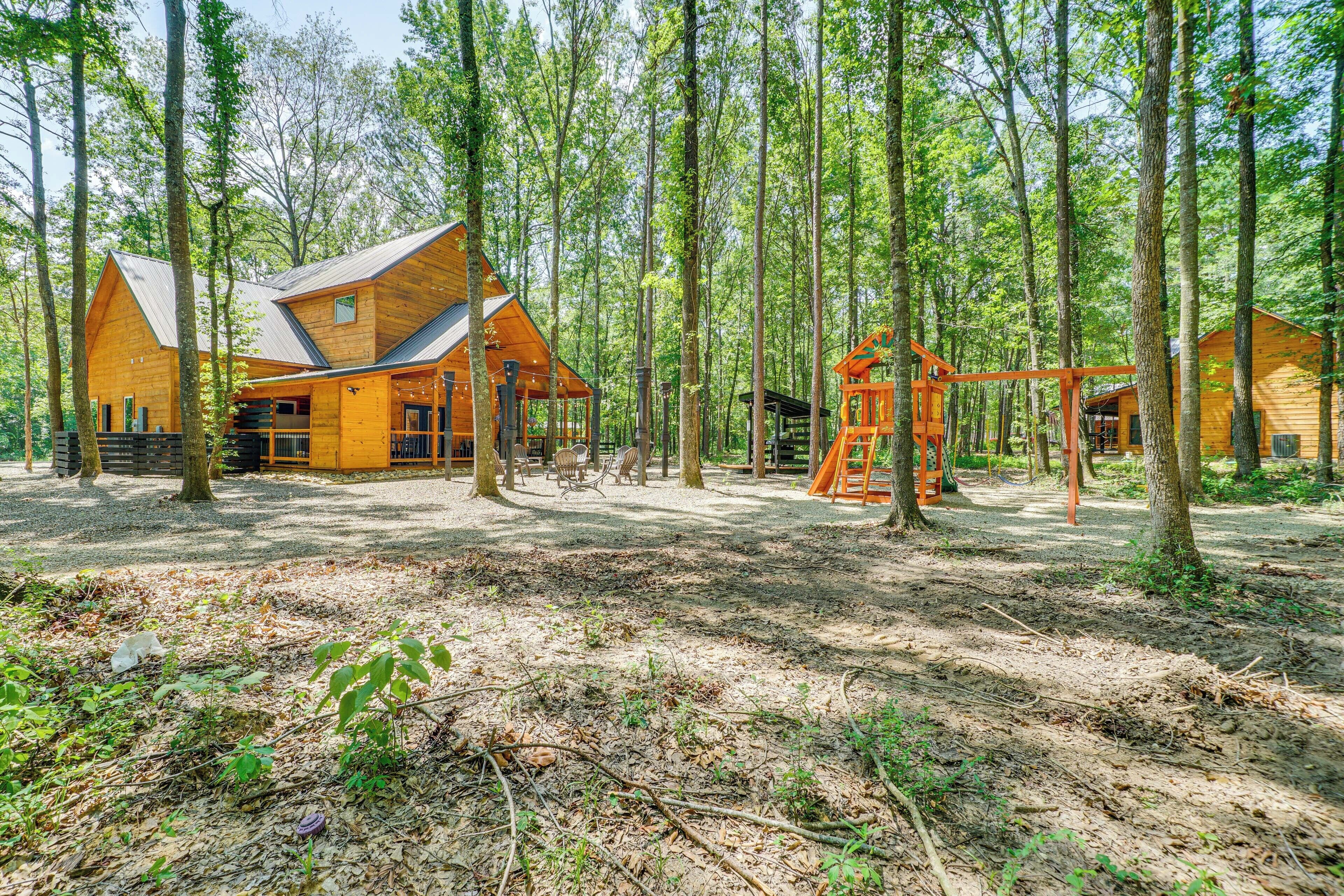 A cabin with a sloped roof, surrounded by tall trees in a forest.