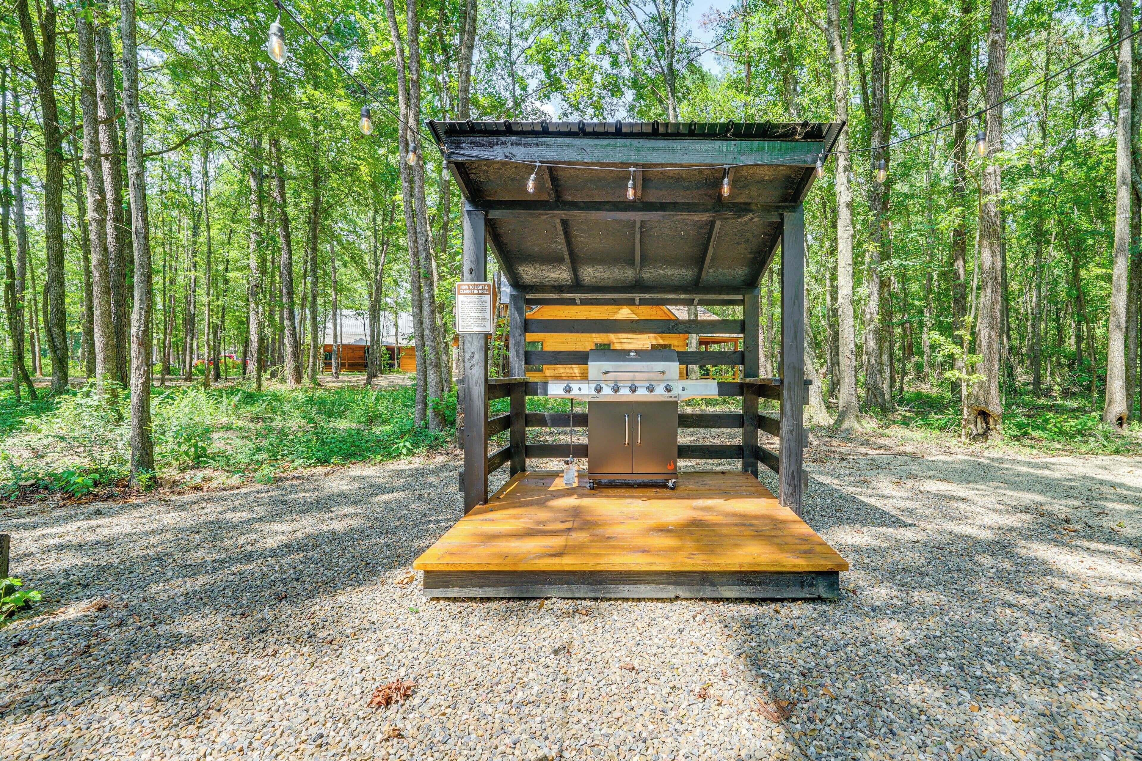 A covered outdoor grill area in a forested setting.