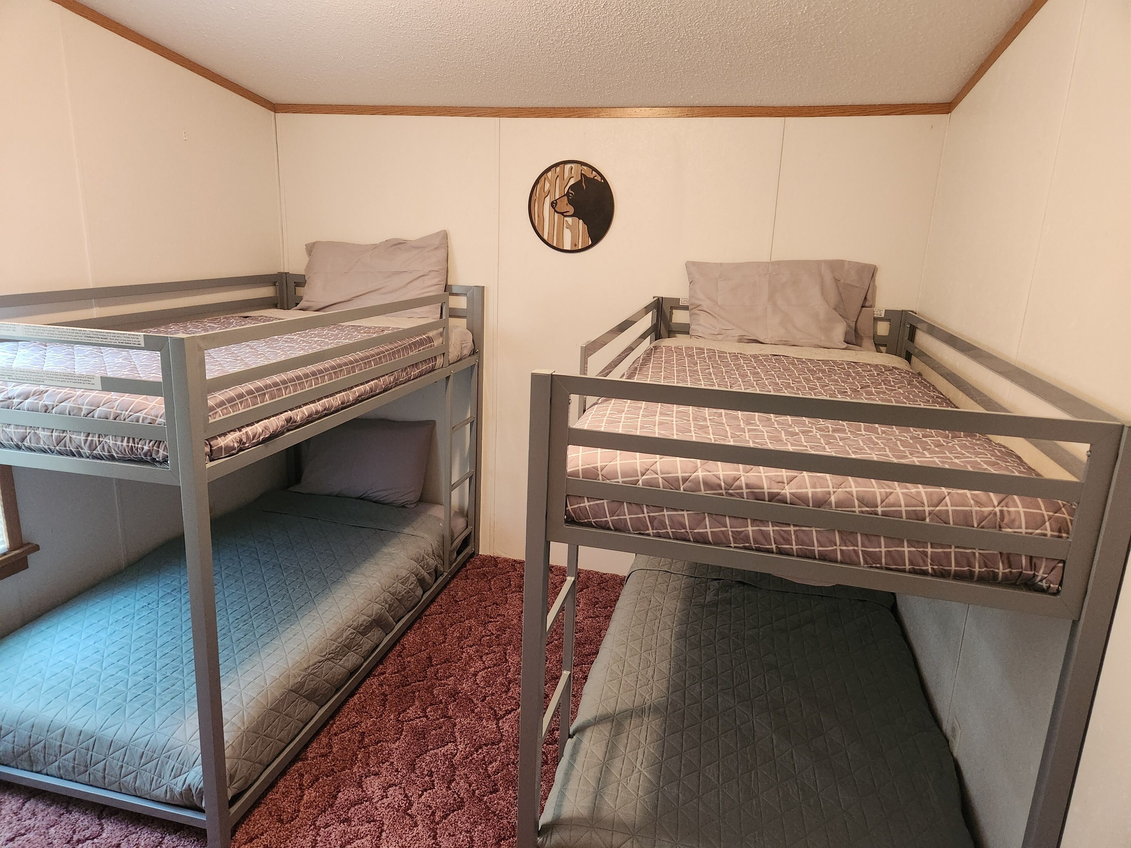 A dormitory room with bunk beds, a red carpet, and a wall clock.