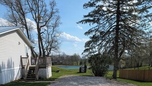 A gravel driveway leading to a house with a wooden deck and stairs. - Hunters Haven a charming 3-br house in welcoming Piedmont Ohio with AC, Wi-Fi.  (Freeport)