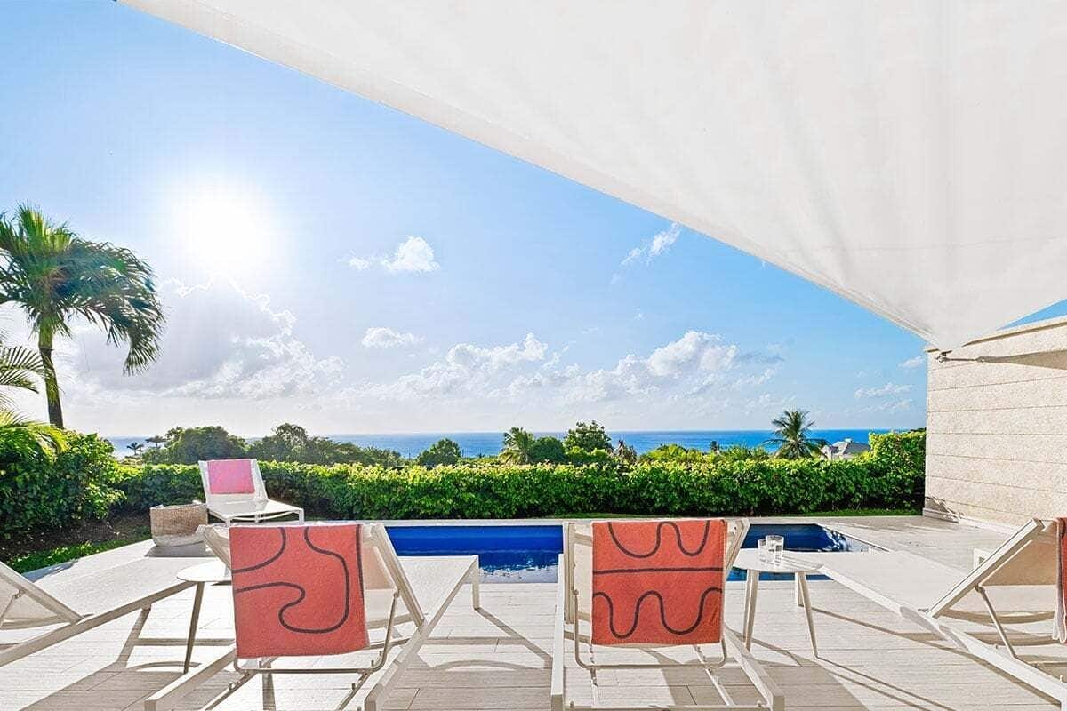 Ein Poolbereich mit Liegestühlen und Blick auf den Ozean.