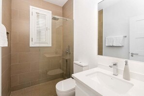 Une salle de bain avec une douche à parois de verre, des toilettes, un lavabo avec un miroir et un porte-serviettes.