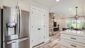 A modern kitchen with a stainless steel refrigerator, white cabinetry, and a stone accent wall. - Chalet Central Park City! 3 Bedroom Home by RedAwning (Park City)