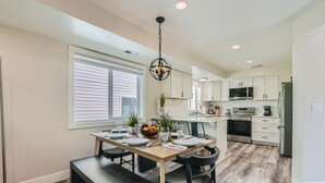 A modern kitchen with white cabinets, a wooden dining table, and a built-in oven. - Chalet Central Park City! 3 Bedroom Home by RedAwning (Park City)