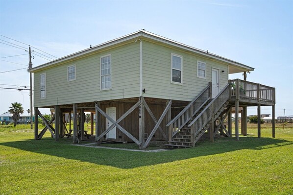 A two-story house with a wooden deck and a staircase.