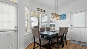 A dining area with a dark wooden table, four chairs, and a hanging light fixture. - Sea View Cottage - 110 Ponce De Leon 3 Bedroom Home by RedAwning (Dauphin Island)