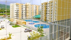 Un immeuble résidentiel doté de nombreux balcons, d’une piscine et d’un espace de stationnement.