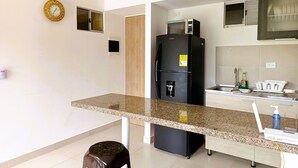 Une cuisine moderne dotée d’un plan de travail en granit, d’un réfrigérateur noir, d’un four à micro-ondes et d’un évier.