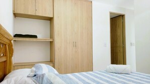 Une chambre à coucher avec un lit, une armoire en bois et une porte donnant sur une autre pièce.