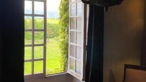 Una habitación con un ventanal grande, una silla y una lámpara colgante.