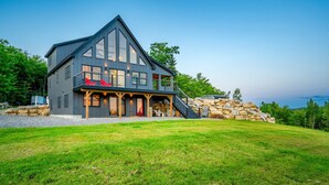 A modern two-story house with a stone foundation, a balcony with red cushions, and a staircase leading to the upper level. - The Best Mountain Views! You can't stop looking at them! (Hanover)