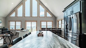 A spacious kitchen with a large island, high ceilings, and large windows offering views of the outdoors. - The Best Mountain Views! You can't stop looking at them! (Hanover)