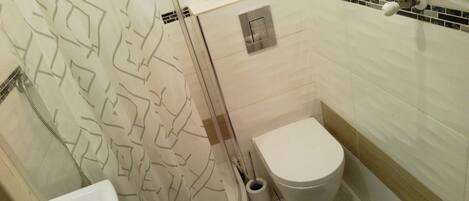 A bathroom with a toilet, a shower, and a sink.