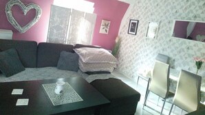 A modern living room with a sectional sofa, a coffee table, and a dining area with chairs. - Beautiful, Quite and Modern Flat, Near the Nature and Railway Station (Karpacz)