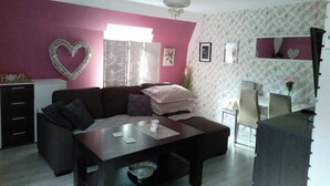 A living room with a dark brown sofa, a wooden coffee table, and a white ceiling fan. - Beautiful, Quite and Modern Flat, Near the Nature and Railway Station (Karpacz)