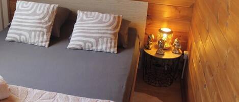 A cozy room with a bed, pillows, a bedside table with a lamp, and a small round table with decorative items.