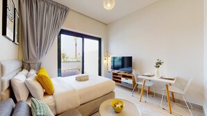 A modern hotel room with a large bed, a TV, a dining area, and a balcony with a view.