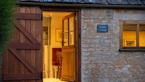 A rustic stone cottage with a wooden door and a sign reading "Stable Cottage". - Dog friendly, two bedroom holiday cottage in heart of Cotswolds (Painswick)