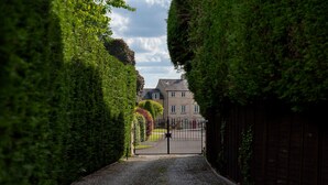 A gravel driveway leading to a gated entrance with a house in the background. - Dog friendly, two bedroom holiday cottage in heart of Cotswolds (Painswick)
