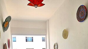 Uma varanda com um sofá, duas cadeiras, uma mesa redonda pequena e pratos decorativos na parede.