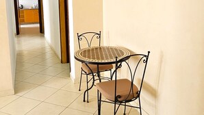 Um corredor com área de jantar, apresentando uma mesa redonda e cadeiras, um quadro na parede e vista para outro cômodo.