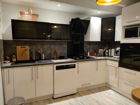 A modern kitchen with white cabinets, a black stove, a microwave, and a dishwasher.