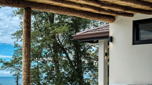 Un espace piscine agrémenté d’une pergola, d’un coin salon et offrant une vue sur la mer.