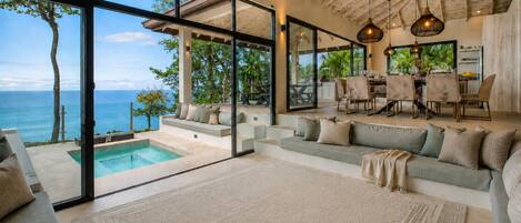 A modern interior with a pool, seating area, and a view of the ocean.