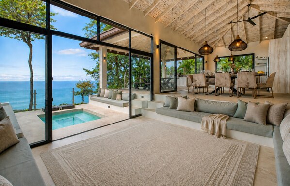A modern interior with a pool, seating area, and a view of the ocean.