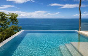 A clear blue pool with a view of the ocean and a distant island.