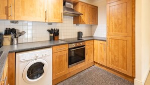 A kitchen with wooden cabinets, a built-in oven, a dishwasher, and a stainless steel range hood.