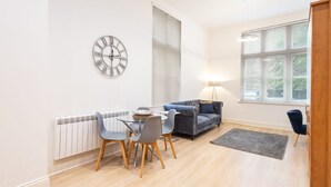 A modern living room with a dining area, featuring a clock, a sofa, a lamp, and a radiator. - Host Stay The Cathedrals (Durham)